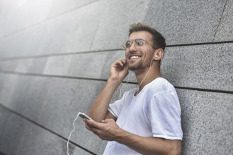 Earphones concept. People, technology, travel and tourism, man with earphones, smartphone on city