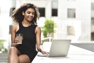 Young attractive Mixed-race girl with beautiful afro hair who is smiling looking at her laptop