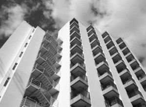 Monochrome angled detail view of an old 1960s white concrete apartment building with steps and