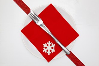 White plate and red Christmas decoration on the white wooden table.Top view.Flat Lay Image