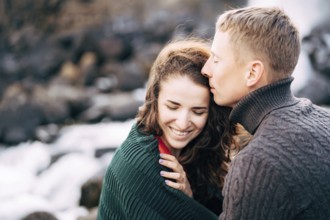 The guy hugs the girl, kisses her on the forehead. The girl smiles.