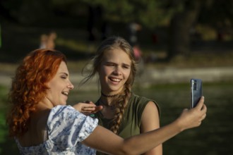On a sunny day, two close friends enjoy each others company, laughing and taking a fun selfie