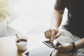 Smartphone in jungen Mann Hand mit digitalen Tablet und Kaffee