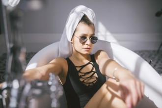 Young caucasian woman with towel on head and sunglasses getting spa treatment in a beauty salon,
