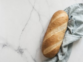 British White Bloomer or European Baton loaf bread on white marble background. Top view or flat lay