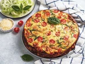 Zucchini pie and ingredients on gray background, copy space left. Delicious savory pie with