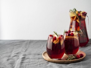 Winter sangria on tabletop with gray linen tablecloth. Jugful of sangria and glasses with with