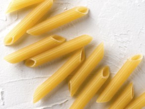 Raw pasta as food background. Italian Penne Rigate Macaroni Pasta on textured white background.