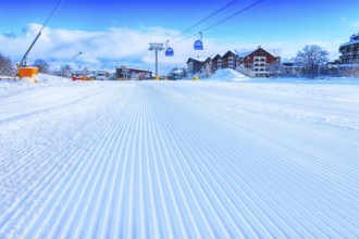 Close-up groomed snow at Bansko resort, Bulgaria panorama with ski slope and cable car lift