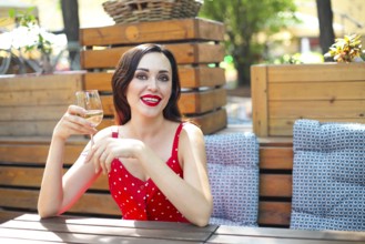 Close up portrait of brunette woman wearing polka dots dress having wine in a restaurant