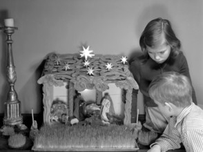 Christmas in the 1950s. Two children with a nativity scene, infant Jesus resing in a manger, Mary