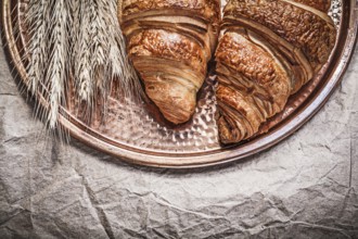 Ripe wheat rye ears fresh rolls copper tray on wrapping paper