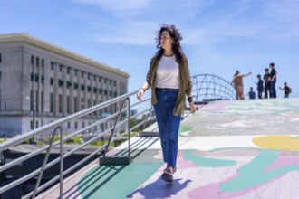 Confident woman strolling along a colorful walkway in a lively city