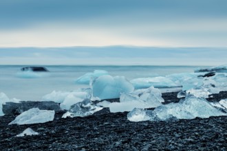 Ice formations along the ocean shoreline under a serene blue sky, creating a cold feeling,