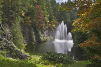 A fountain in the deep lake surrounded by park and lawns