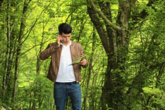 Handsome young man hiking in lush green mountain scenery, walking up the hill, looking down