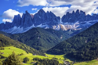 Odle mountain peaks surround the green alpine meadows of the valley. Dolomites, Val de Funes valley
