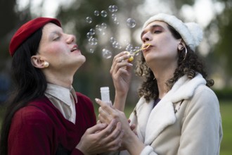 Transgender female couple blowing bubbles in a park