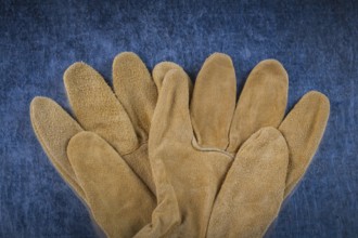 Leather brown construction gloves on scratched metallic surface close up version building concept