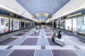 Modern shopping centre with blue ceiling and symmetrical architecture, surrounded by shops