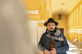 Portrait of a stylish handsome young man with a scarf outdoors. A serious man wearing a scarf, hat