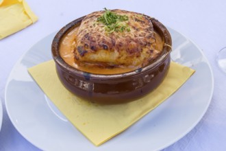 Portion of lasagna bolognese in a terracotta ramekin lay on a white plate