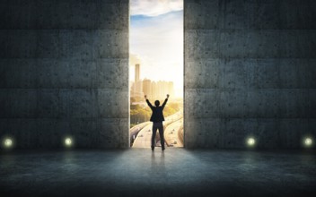 Success businessman cheering against concrete wall with huge door, sunrise scene city skyline