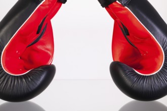 Red and black boxing gloves on a glass table isolated on white background