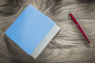 Vintage blue notepad red ballpoint pen on wooden board