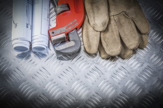 Pipe wrench construction plans leather safety gloves on corrugated metal background building