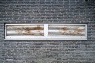 Rusted ventilation grilles in a brick wall