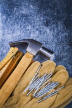 Leather safety working gloves set of construction nails wooden meter and claw hammer on scratched