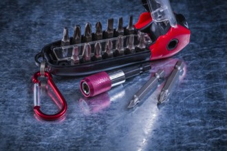 Screwdriver with muunction bit set on scratched metallic background