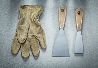 Putty knife safety gloves on concrete surface construction concept