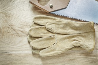 Leather protective gloves handsaw on wooden board construction concept