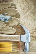 Protective gloves wooden meter claw hammer nails on wood board construction concept