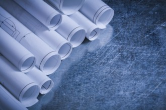 Rolled up blueprints on scratched vintage metallic background construction concept