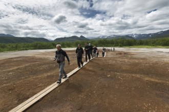 NALYCHEVO, KAMCHATKA, RUSSIA, JULY 30, 2014: Tourists walk on wooden deck, overlooking Thermal Pad
