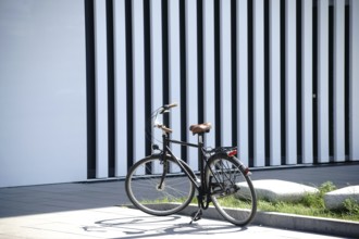 An old bicycle stands in front of the façade of a modern building