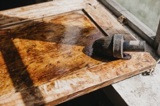 Varnished wooden surface under sunlight, highlighting texture with brush nearby