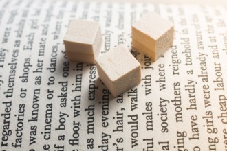 Wooden toy cubes placed on a book page in English