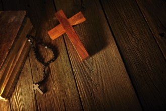 Christian cross on wood bible and rosary beads over wooden vintage background