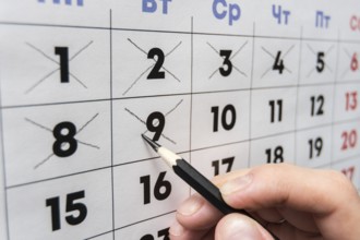Pencil crosses out dates on the wall calendar