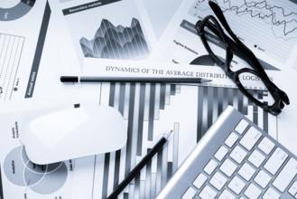 Business workplace with keyboard glasses and financial documents on table