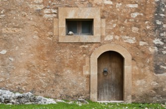 Abstract details of a brown stone wall with an old wooden closed vintage door and a small window