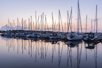 Sailing boats in the harbour reflecting in the water during beautiful sunset