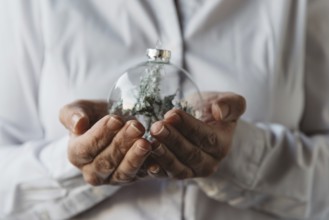 Close-up of woman hands holding Christmas bauble. Focus on foreground
