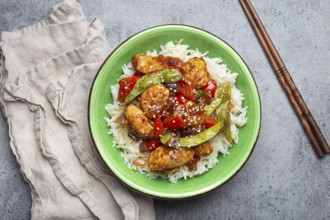 Asian sweet and sour sticky chicken with vegetables stir-fry and rice in ceramic bowl with