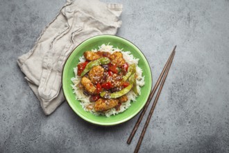 Asian sweet and sour sticky chicken with vegetables stir-fry and rice in ceramic bowl with