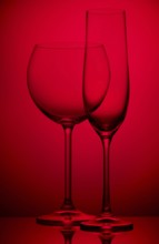Two empty wineglasses on a red background
